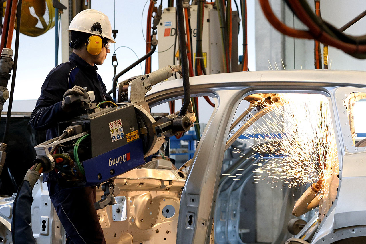 Operário de fábrica trabalha na carroceria de um veículo BMW