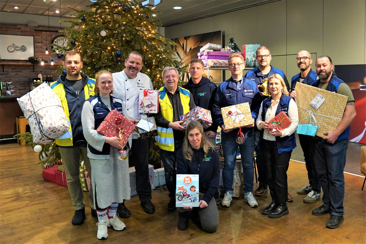 Menschen stehen vor einem Weihnachtsbaum und halten Geschenke in den Händen.
