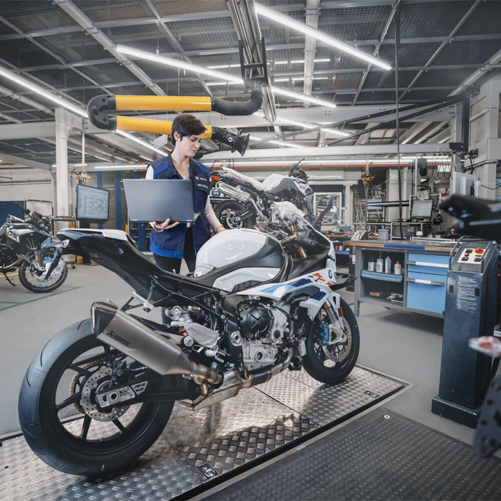 Student inspects a BMW motorcycle with a laptop.