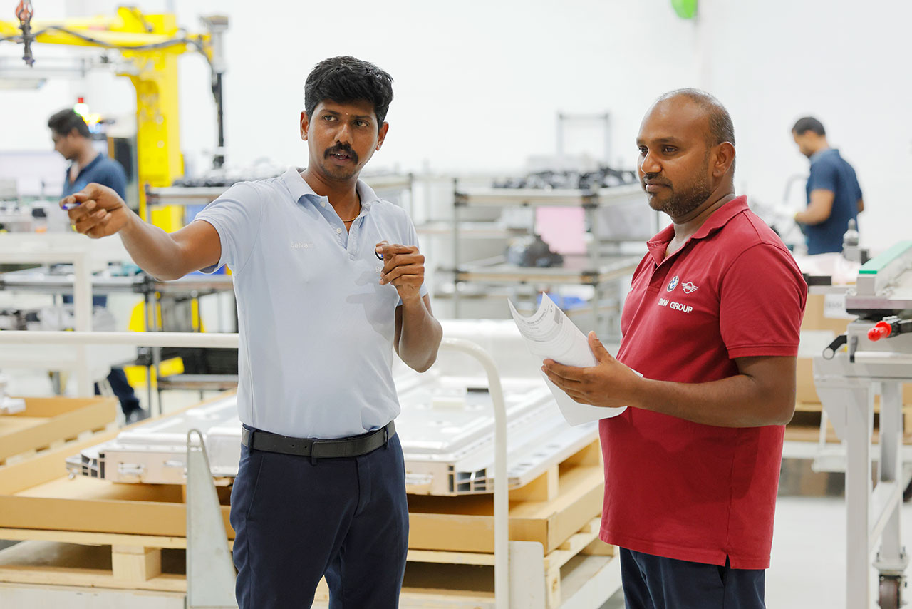 Two factory workers discussing manufacturing processes in the BMW Group workshop.