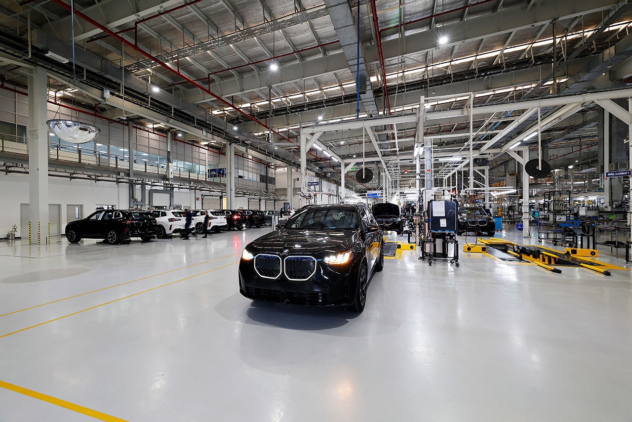 Interior view of the modern BMW manufacturing facility with assembly lines and vehicles.
