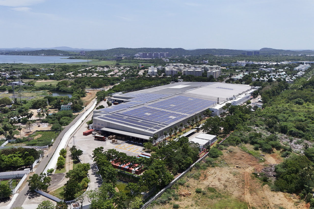 Aerial view of a large industrial building featuring solar panels installed on its roof.