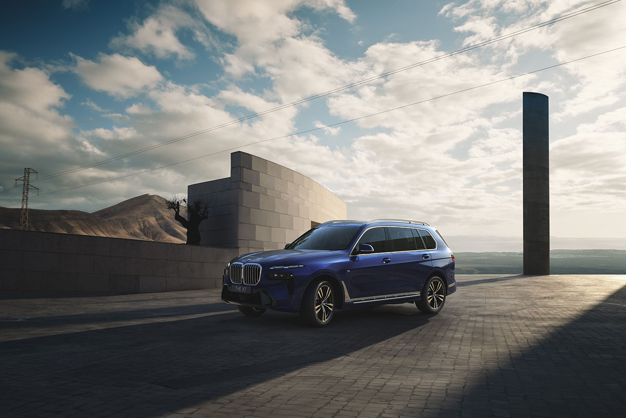  A blue BMW X7 SUV parked in a modern architectural setting during sunset.