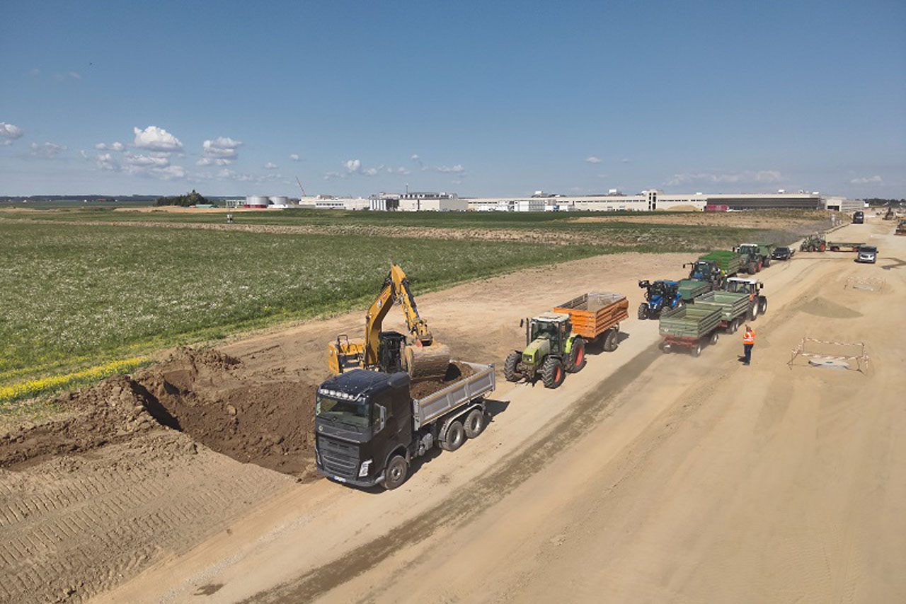 Baumaschinen arbeiten auf einer Baustelle, während sie Erde bewegen und Materialien transportieren.
