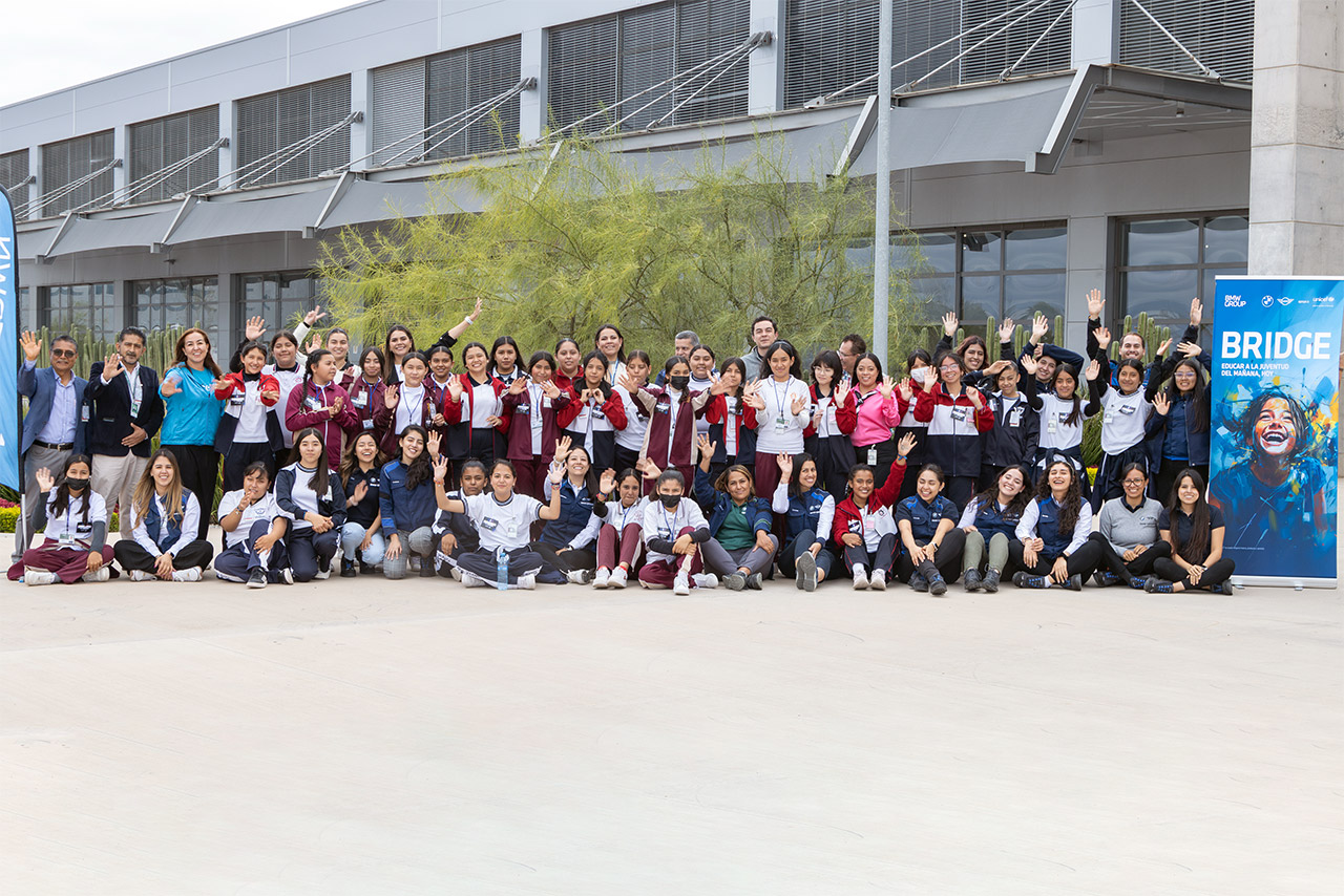 Large group of people smiling and waving at the camera
