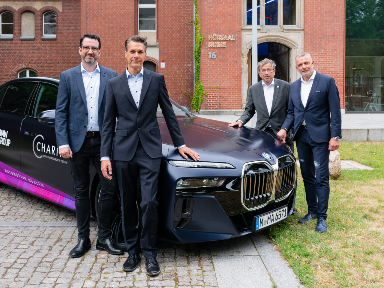 Professor Alexander Meyer, Dr Matthias Franz, Professor Heyo K. Kroemer and Dr Rudolf Bencker beside a BMW 750e xDrive plug-in hybrid research vehicle.