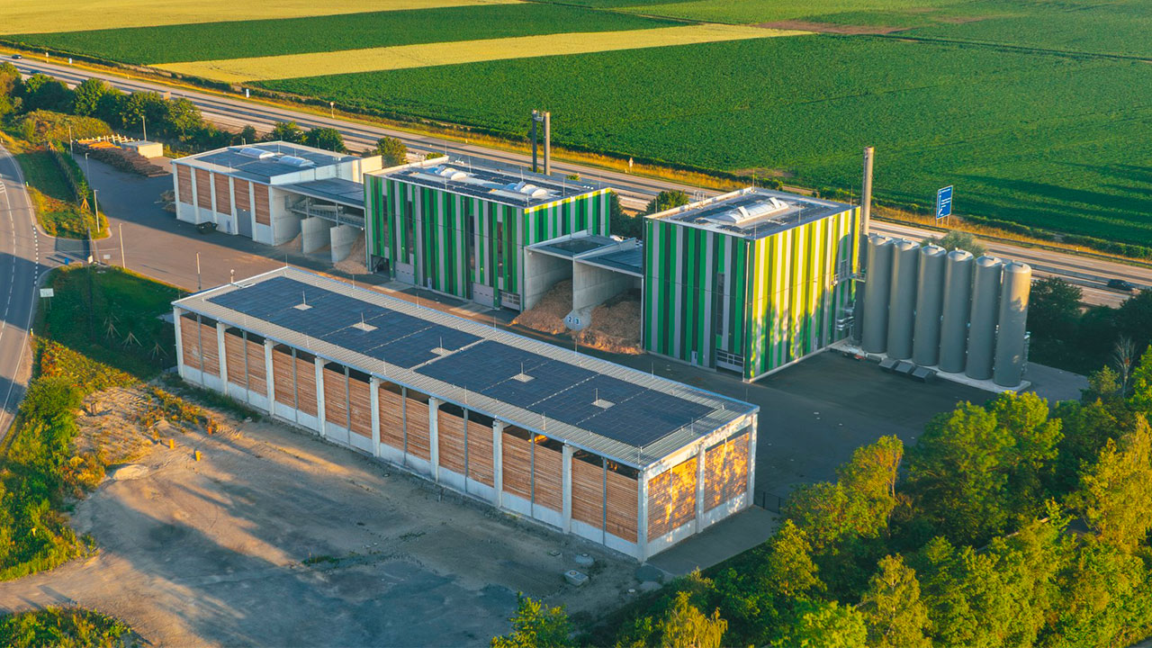 Aerial view of the new Dingolfing biomass heating plant, featuring a storage area for raw materials and connected district heating infrastructure.