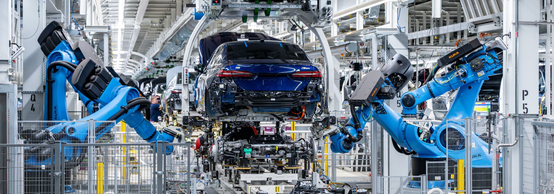 Fahrzeugheck in einer Produktionshalle, umgeben von mehreren Industrierobotern an Montagelinien