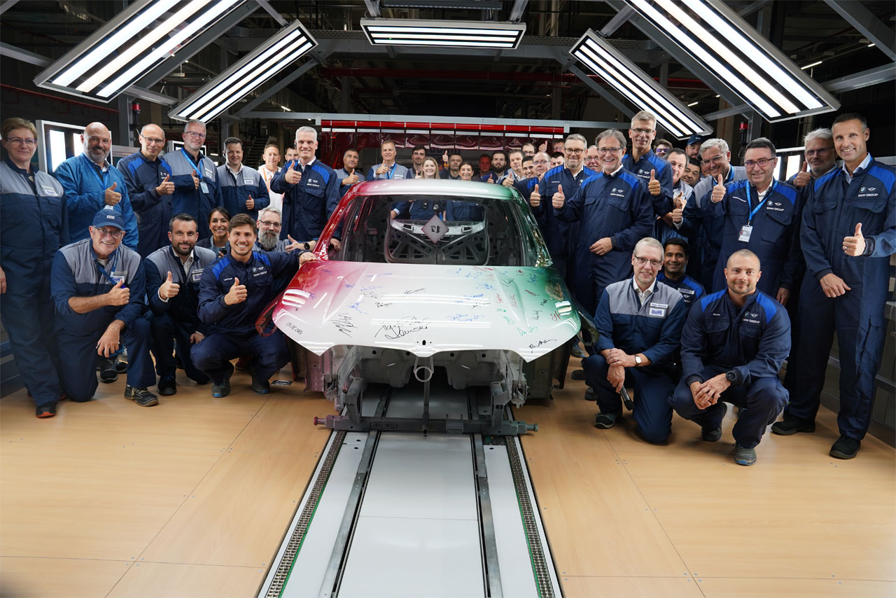 BMW Group production workers standing next to a painted car body.