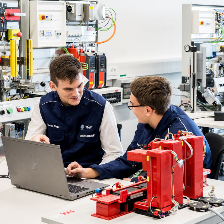 Two men are examining a laptop together, appearing to collaborate on a project or task.
