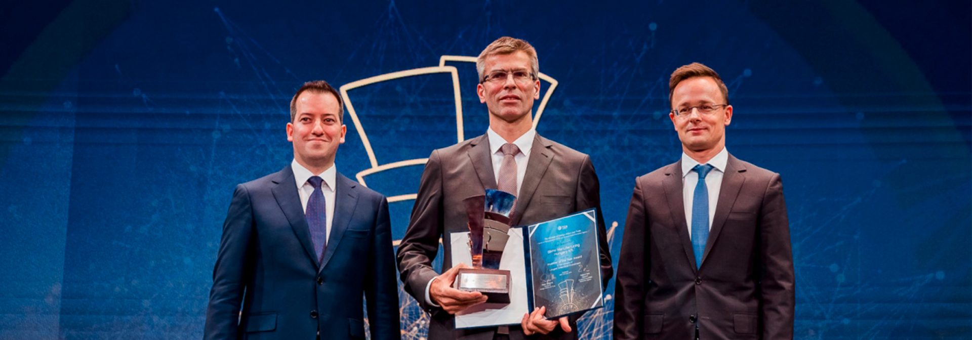 Three man standin in front of a "investors of the year" wall