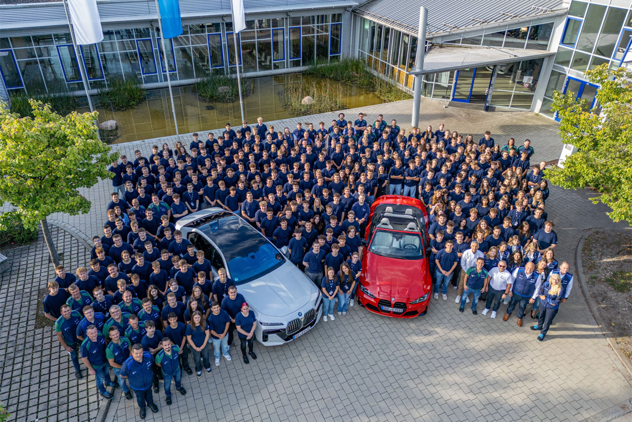 Mitarbeiter von BMW stehen stolz vor der neuen Produktionsstätte in Dingolfing.