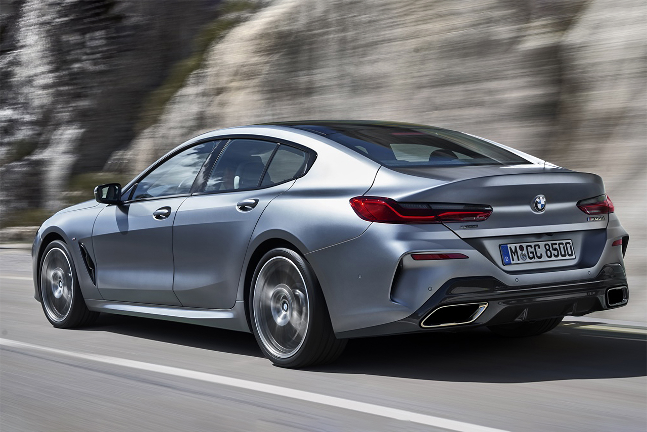 Grauer BMW 8er Gran Coupé fährt an einer Feldwand entlang.