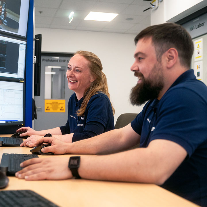 Two experienced employees at the BMW Group are talking on a computer in a production environment.