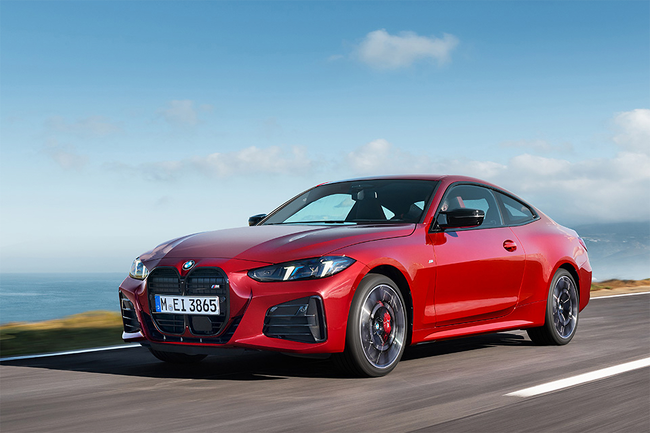 Red BMW 4 Series Coupé driving along the sea.