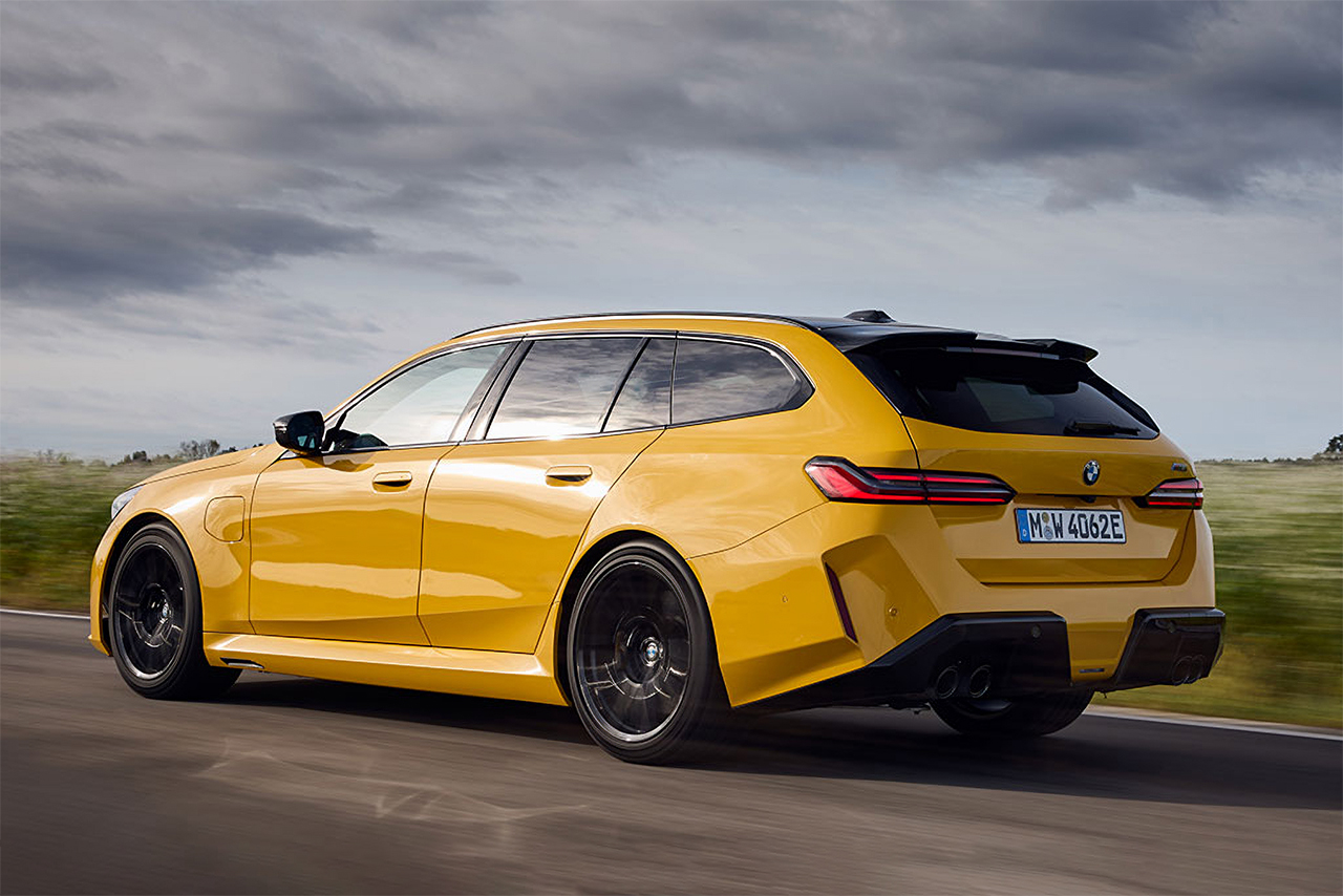 Yellow BMW M5 Touring driving along a country road.