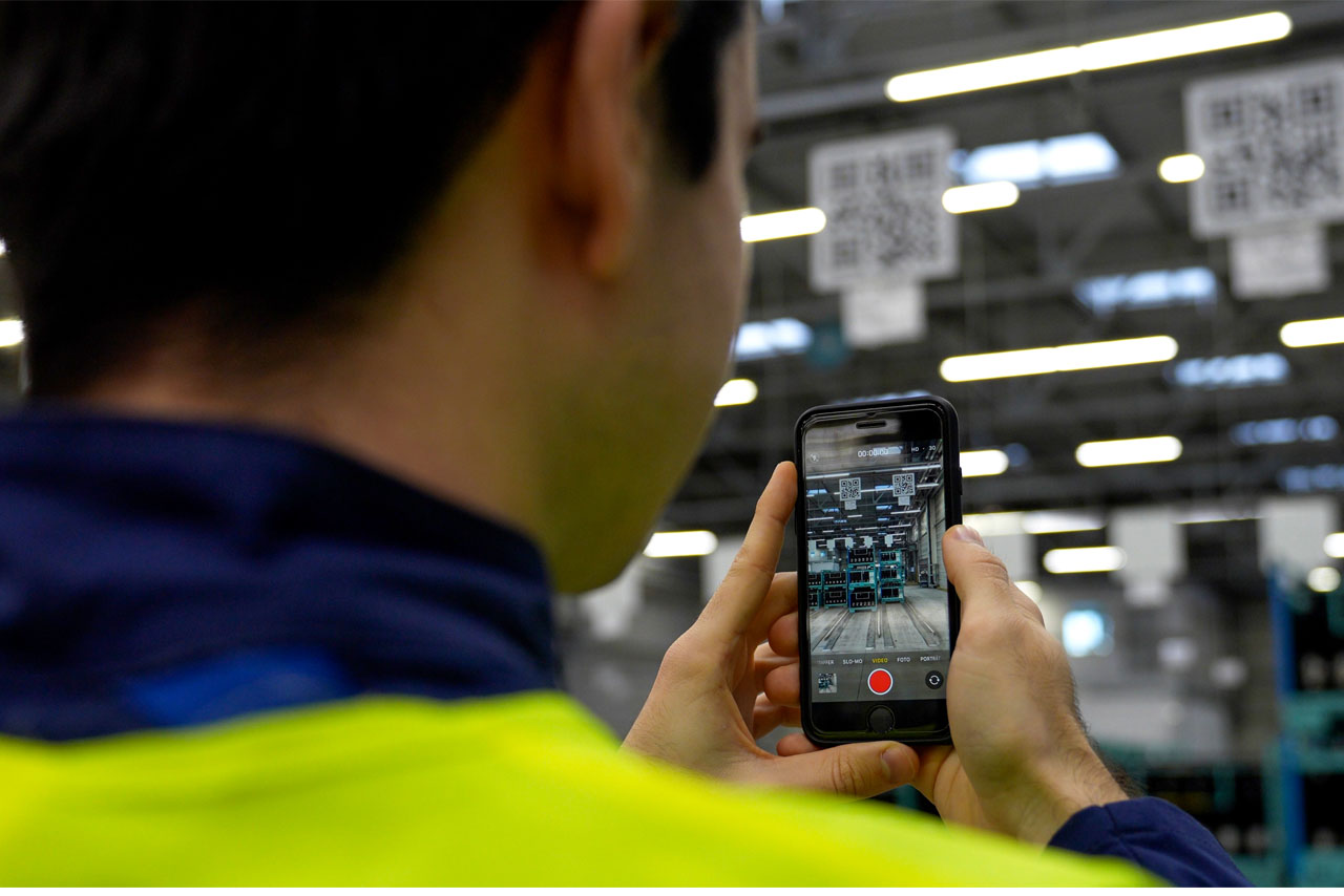 An employee in production at the BMW Group uses his smartphone camera to scan a QR code.
