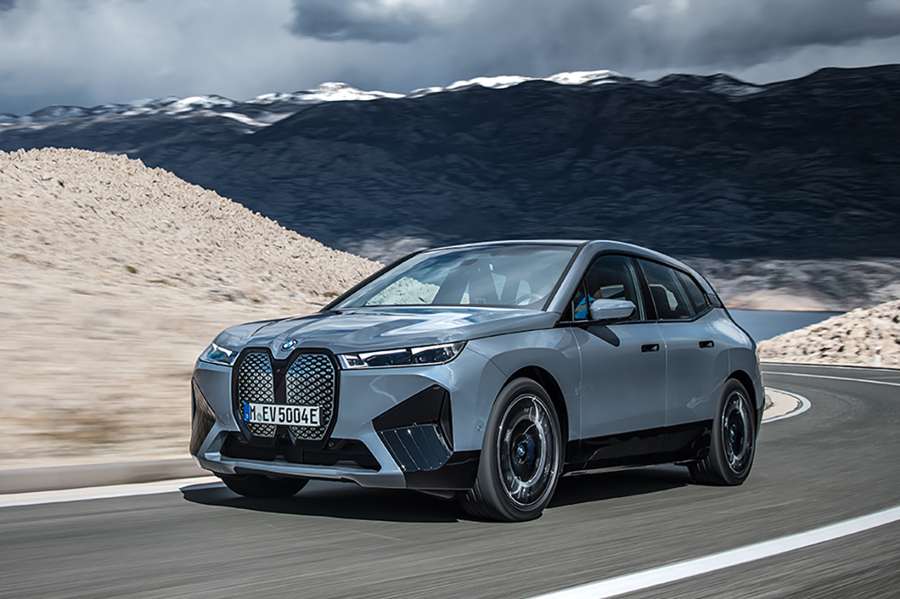 Gray BMW iX driving along a country road.