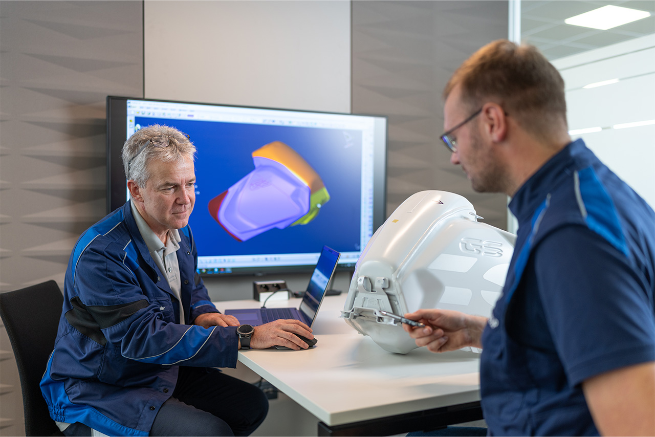 Zwei Mitarbeiter arbeiten zusammen an einem neuen Motorradteil.