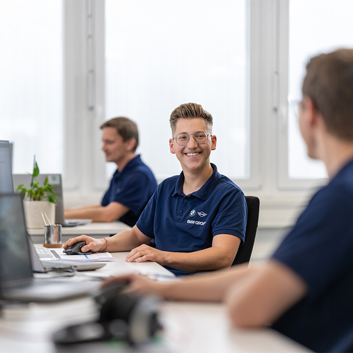 Three experienced employees at the BMW Group work on computers in the office.