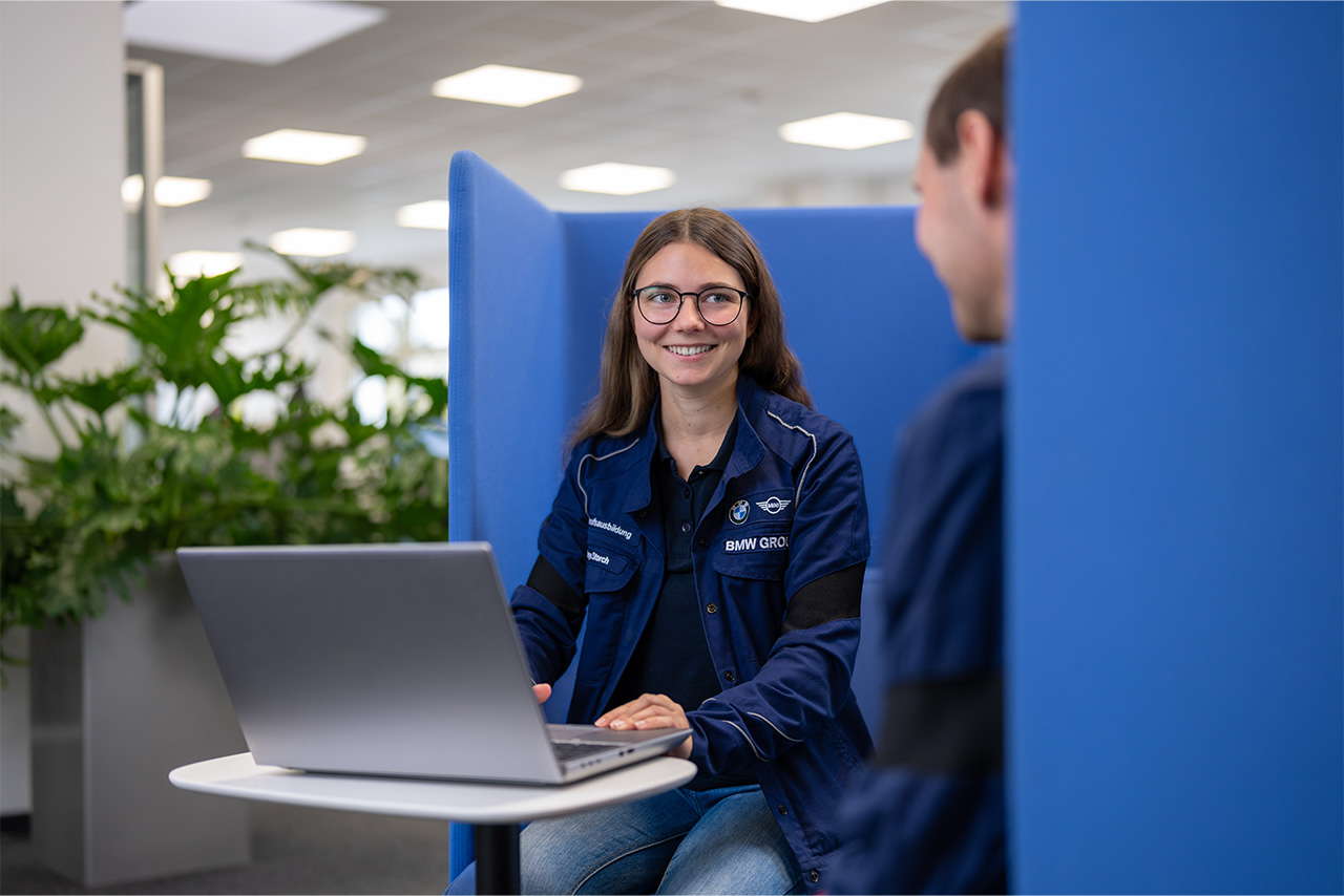 Two young employees work together on a sofa and are in a good mood.
