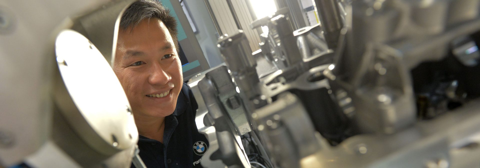An employee is working on the motor of a new BMW vehicle.