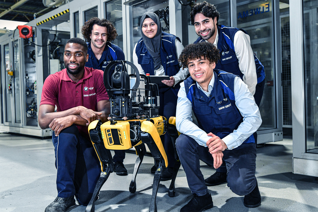 Young apprentices at BMW Group plant Hams Hall are posing for a picture with a robotic dog.
