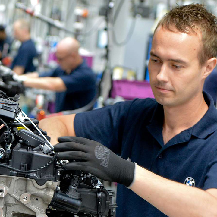 An employee in the BMW Group plant Hams Hall is working on the motor of a BMW vehicle.