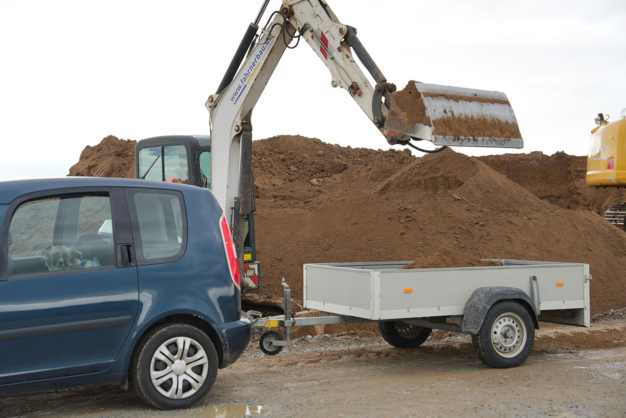 Ein Bagger auf der Baustelle des BMW Group Werks Irlbach-Strasskirchen lädt Erde auf einen Anhänger.