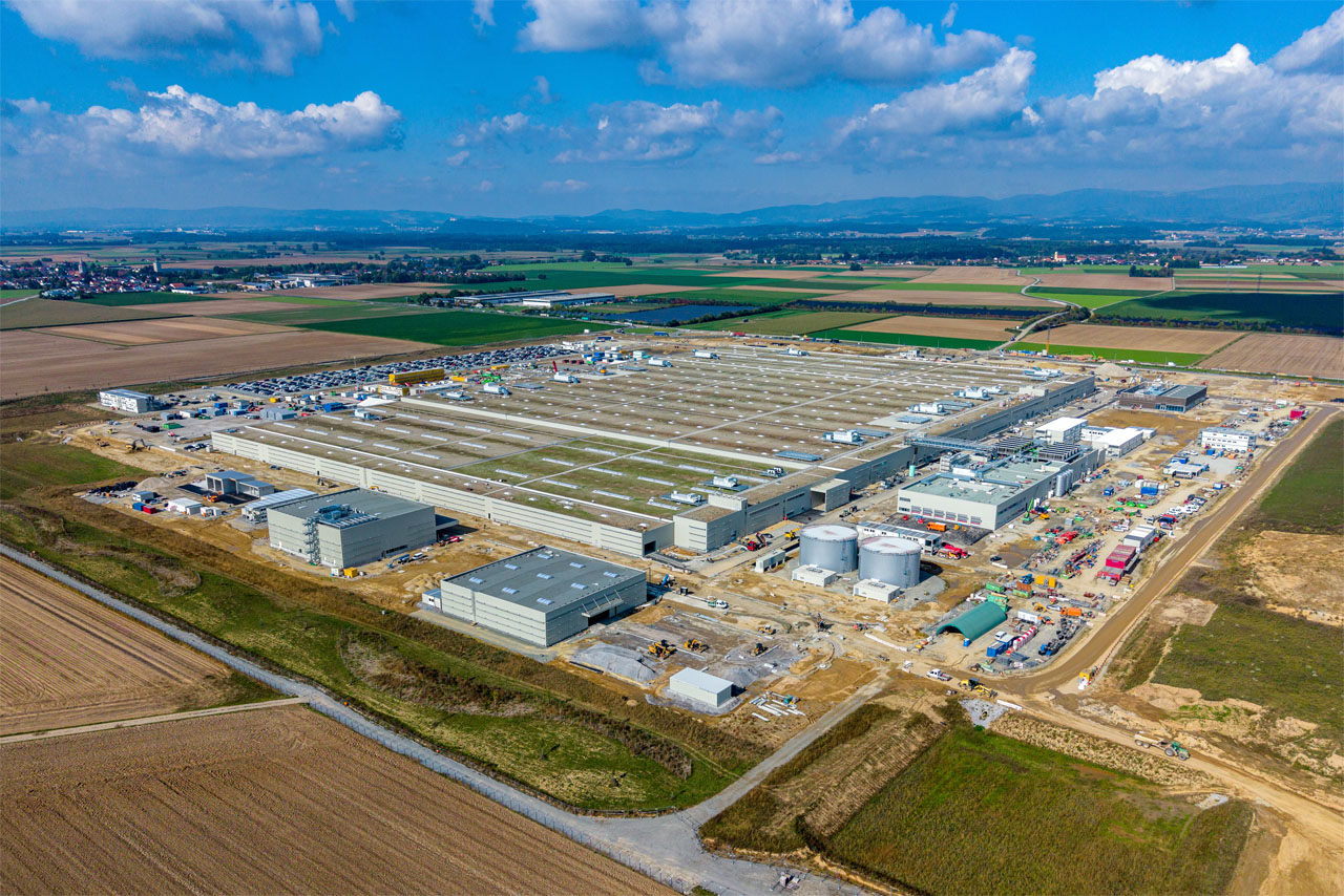 Luftaufnahme eines großen Industriekomplexes mit mehreren Gebäuden und Baustellen in einer ländlichen Umgebung.