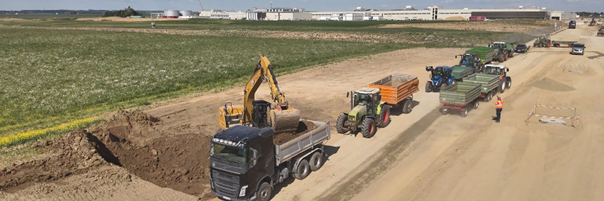 Baumaschinen arbeiten auf einer Baustelle, während sie Erde bewegen und Materialien transportieren.