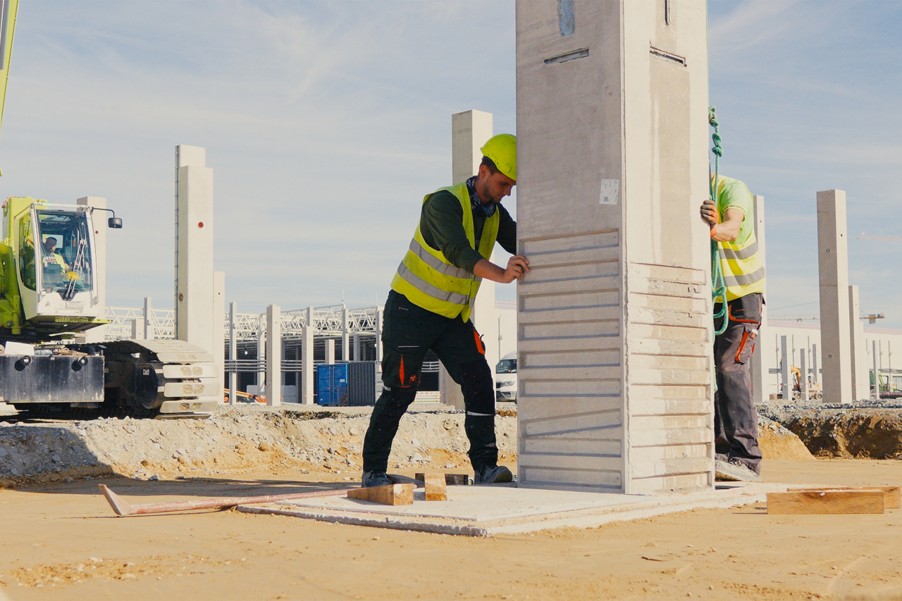 Two construction workers erect the last pillar of the plant for the assembly of high-voltage batteries.