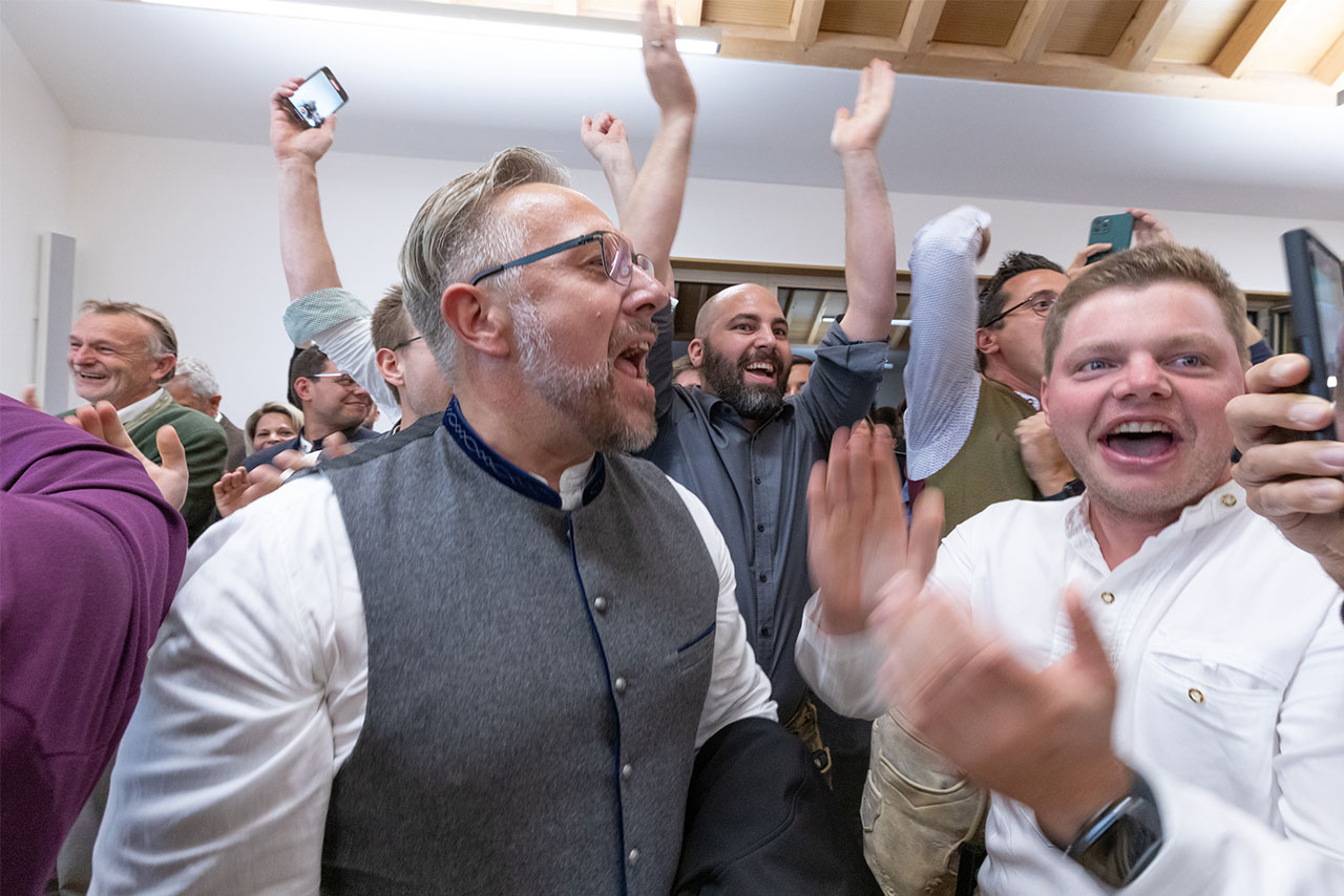 A group of people cheering enthusiastically in a celebratory atmosphere.