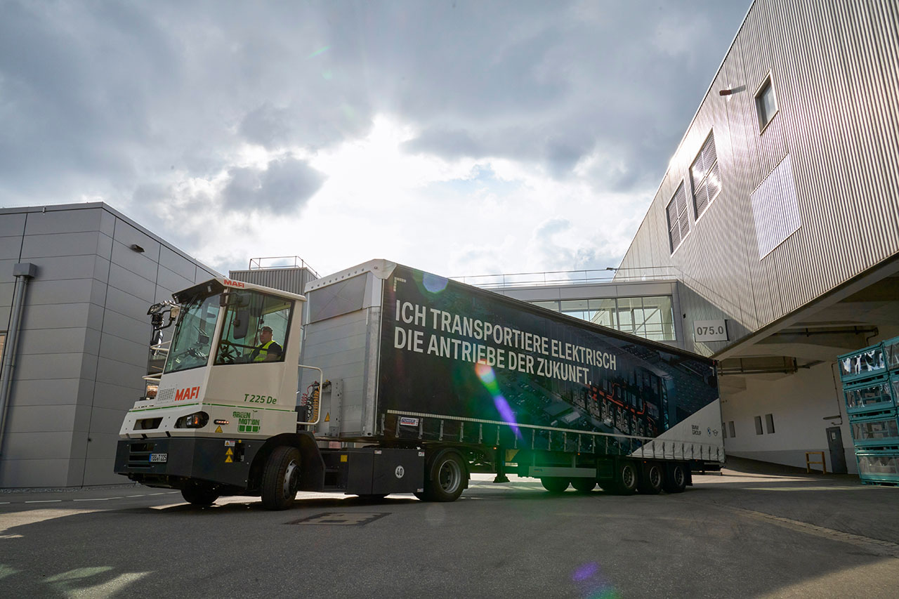A truck with an electric drive drives in front of the BMW Group production halls.