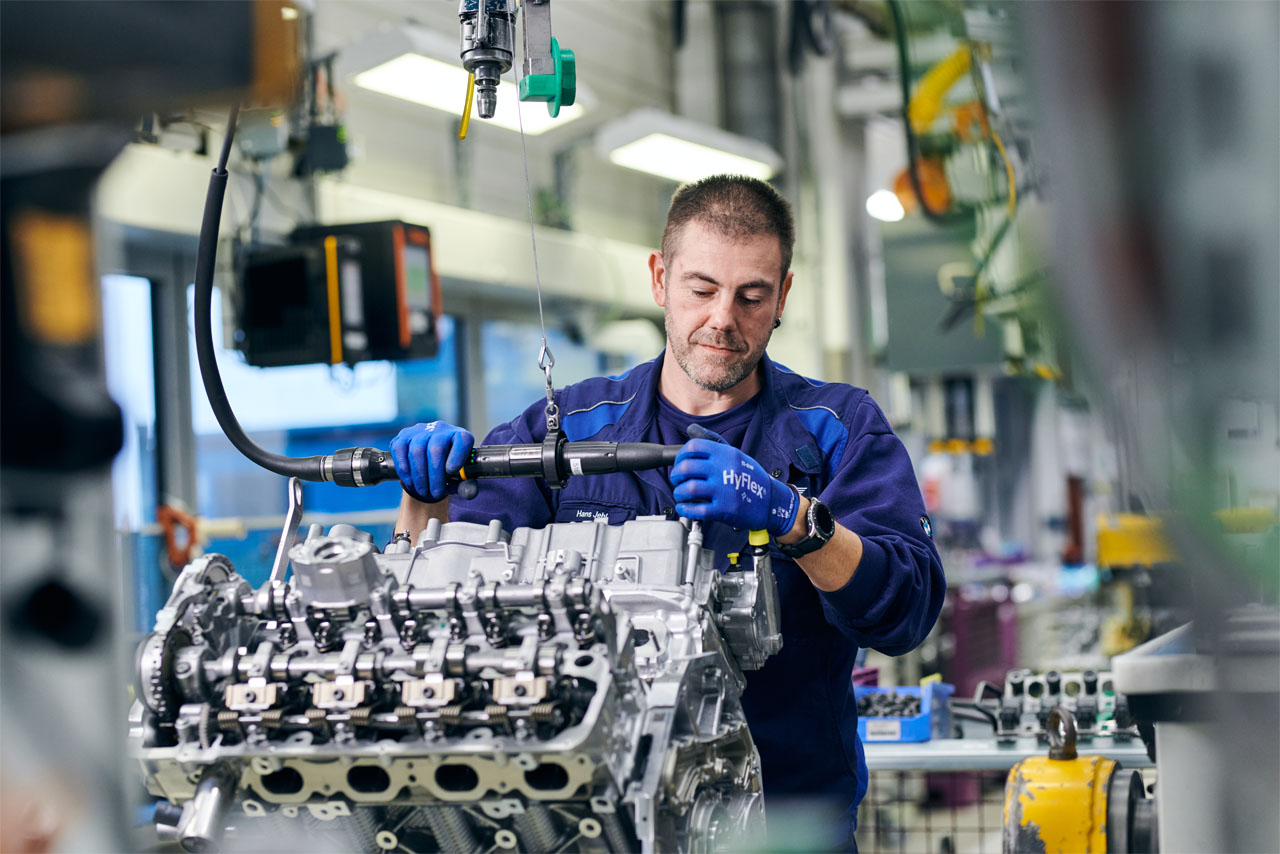 Ein BMW Group Mitarbeiter arbeitet mit modernen Werkzeugen an einem Motor.