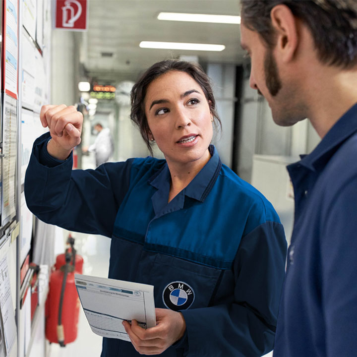Eine erfahrene Mitarbeiterin bei der BMW group erklärt ihrem neuen Kollegen den Arbeitsplan.