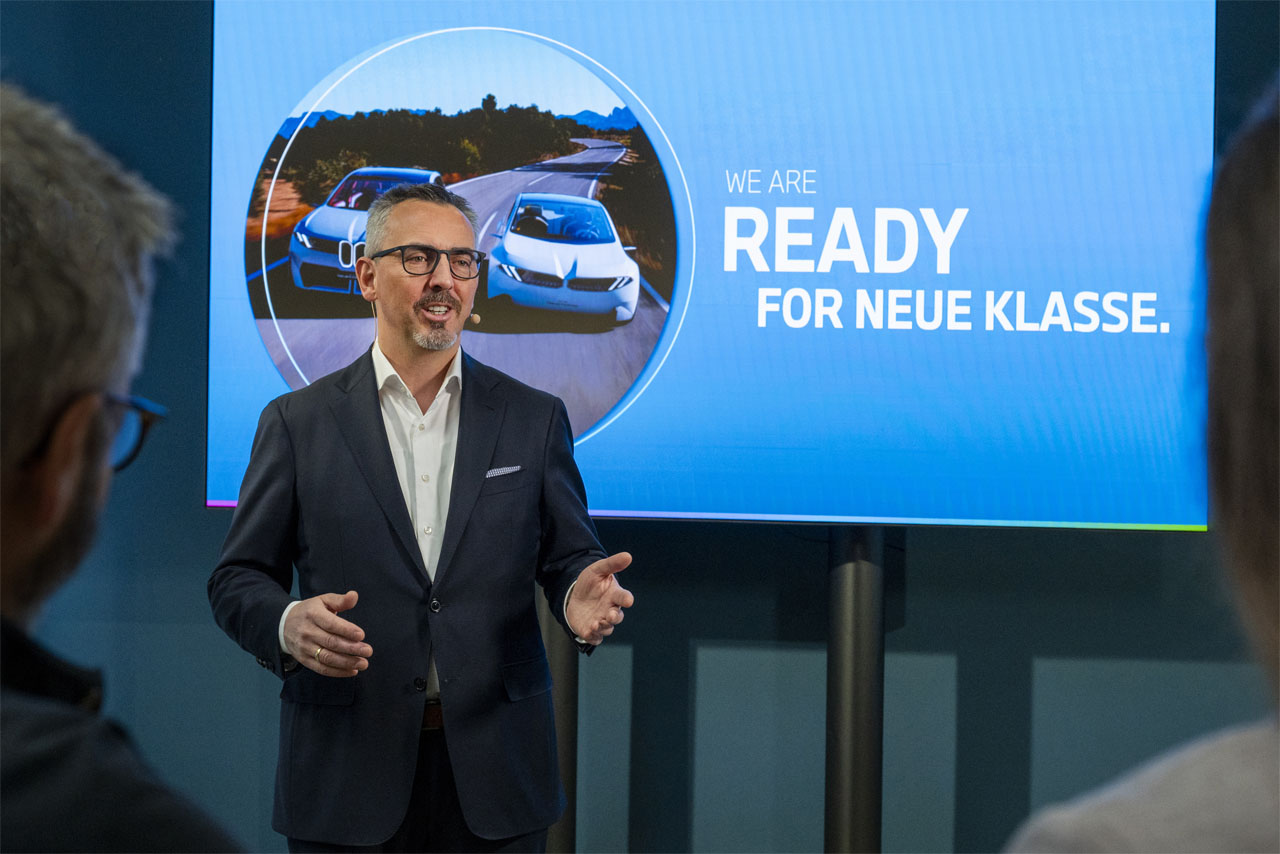 Ein Mann im Anzug hält einen Vortrag vor einer Gruppe von Zuhörern in einem Konferenzsaal.