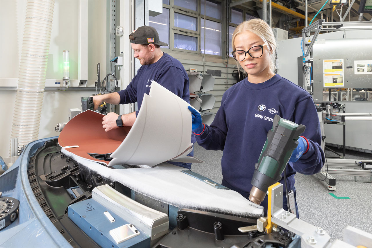 Two employees working on the interior of a vehicle.