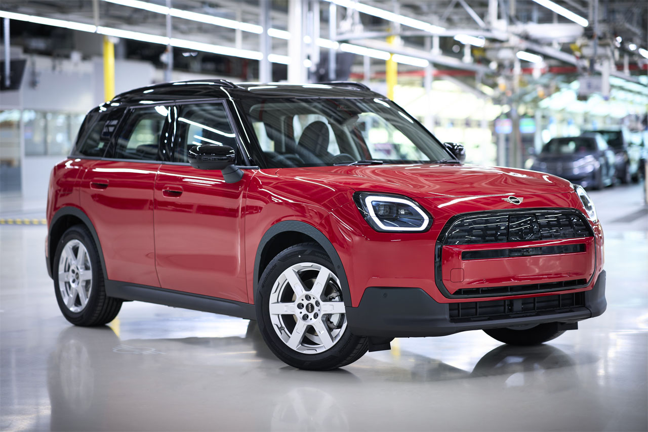 Der neue Mini Countryman steht in einer Fabrik, umgeben von industriellen Maschinen und Montagearbeitsplätzen.