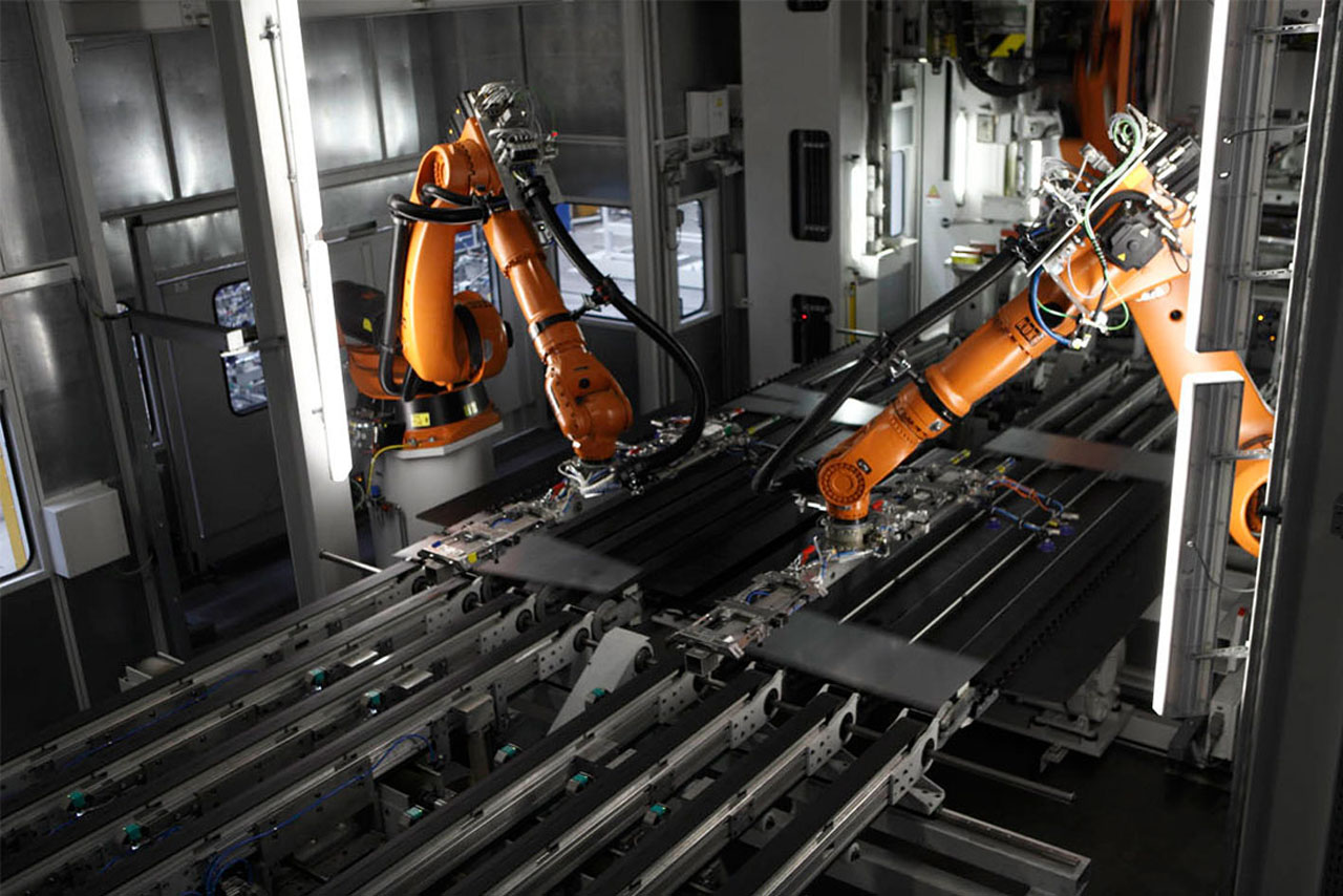 Roboterarme, welche im Presswerk an Fahrzeugteilen arbeiten.