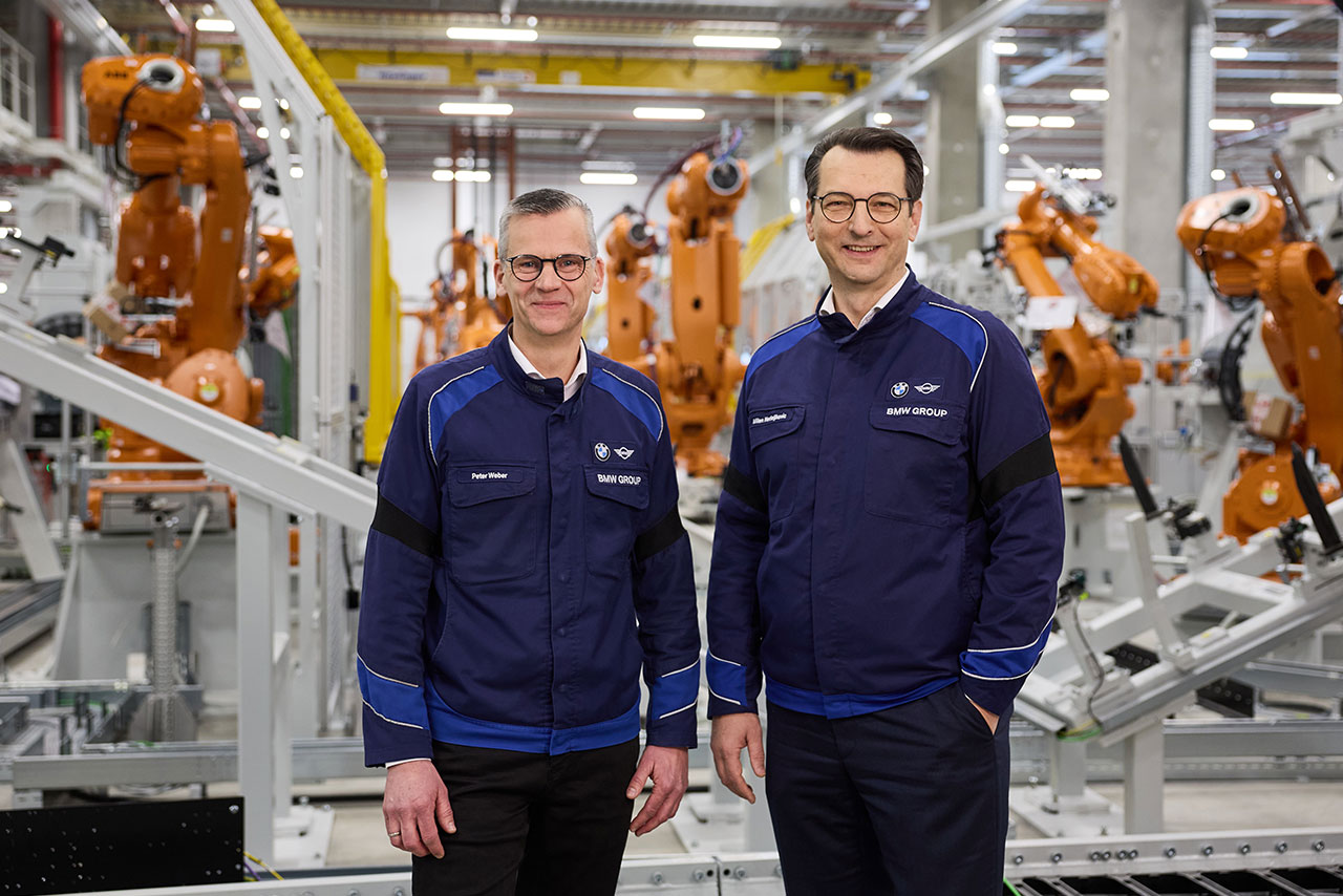 Zwei Mitarbeiter der BMW Group stehen zwischen Produktionsrobotern.
