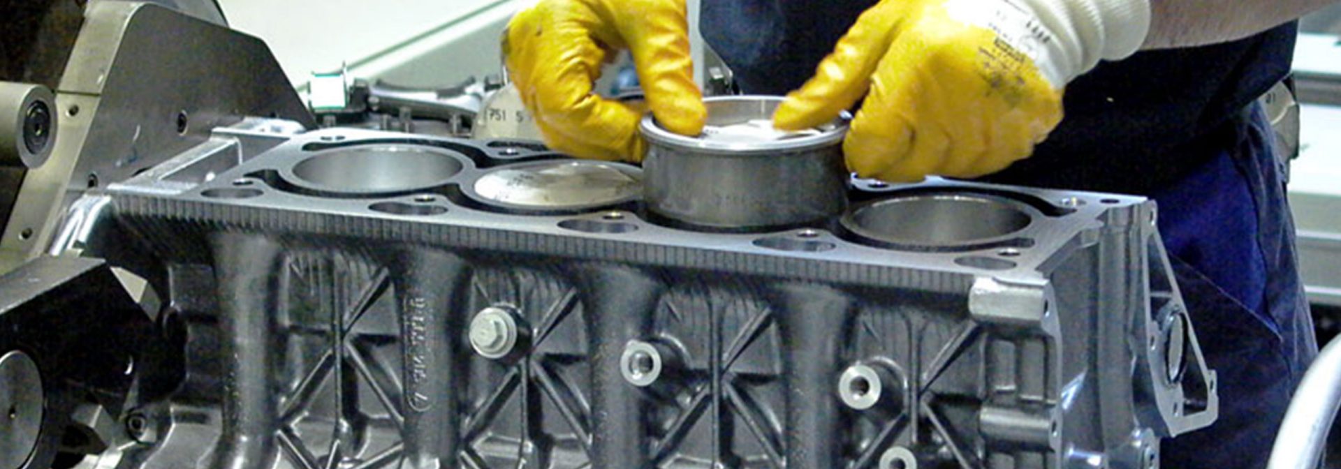 Ein Mechaniker montiert einen Kolben in einen Motorblock.