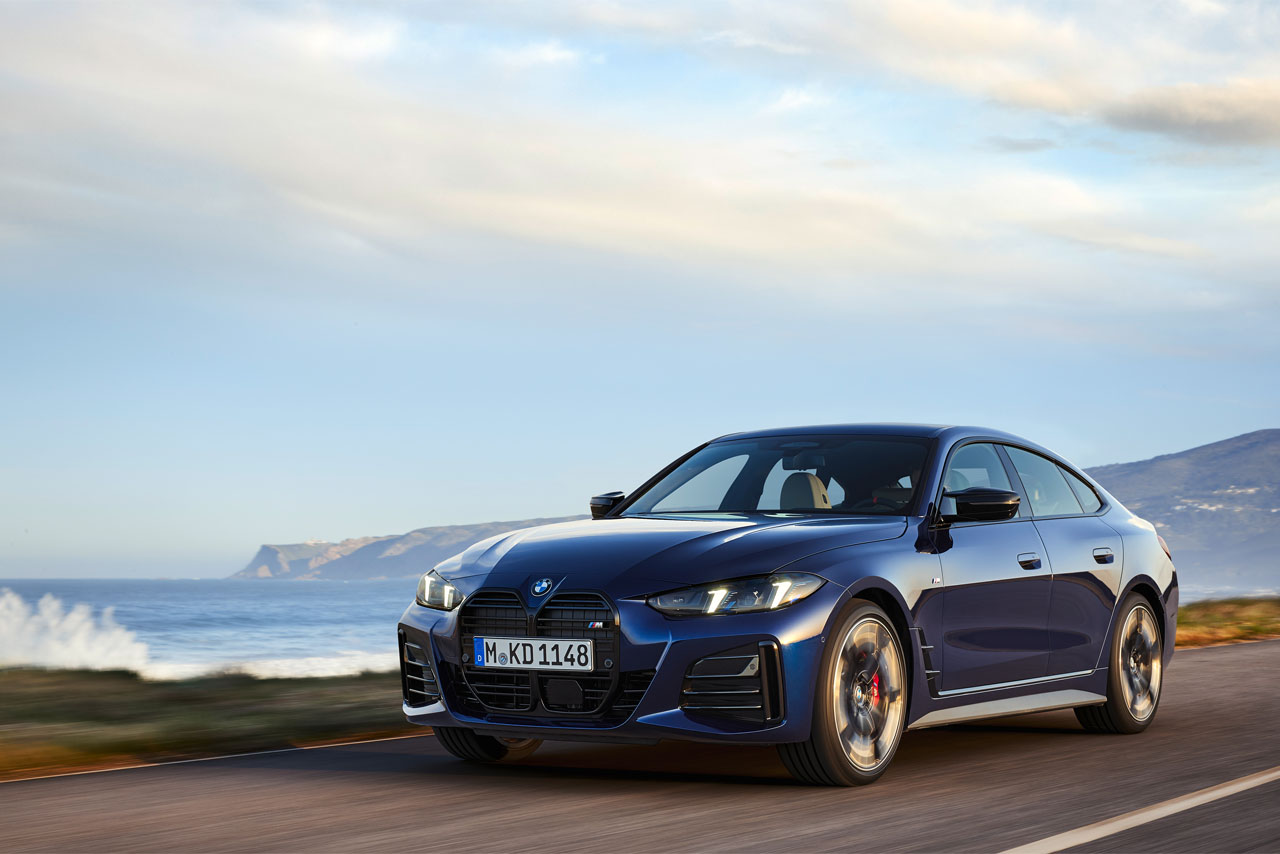 Blue BMW 4 Series Gran Coupé  driving on a country road with an ocean in the background