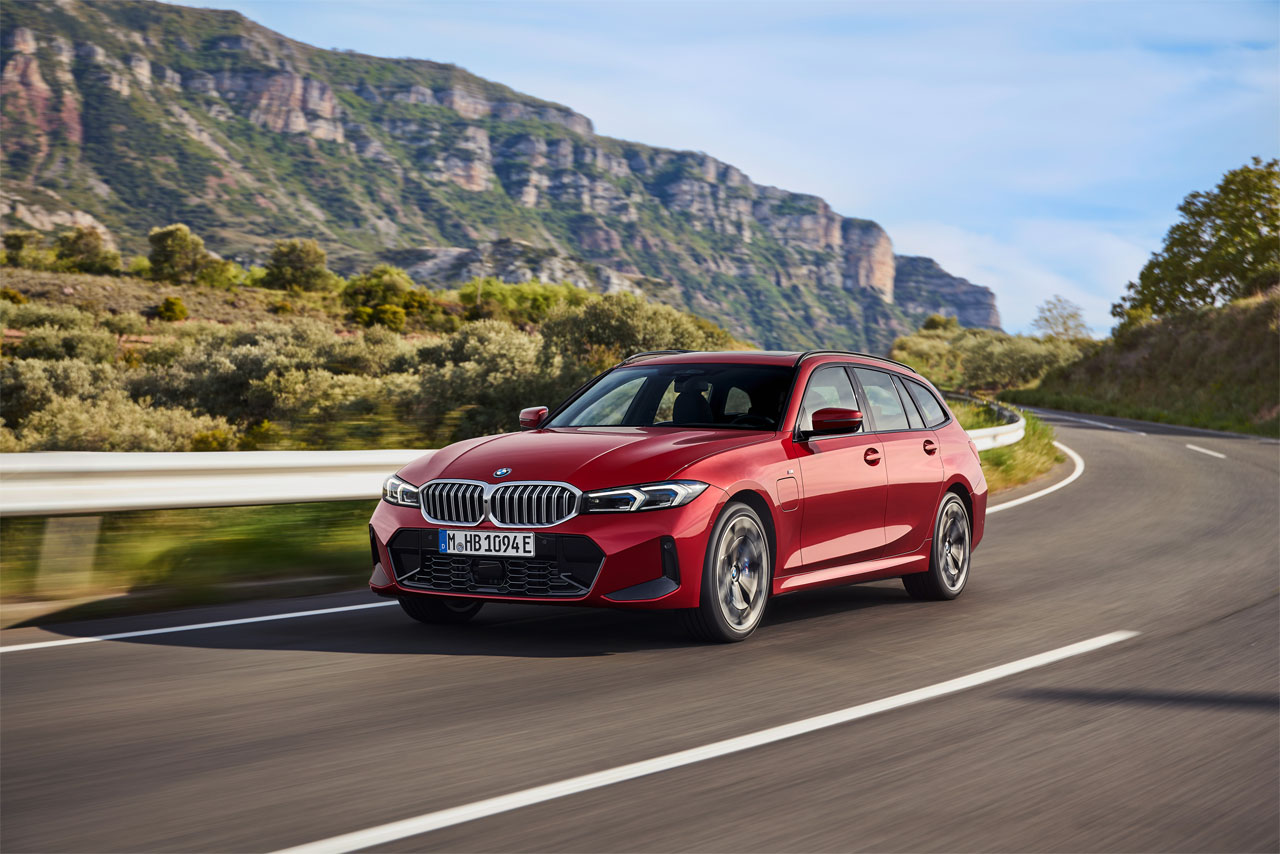 Red BMW 3 Series Touring driving on a country road.