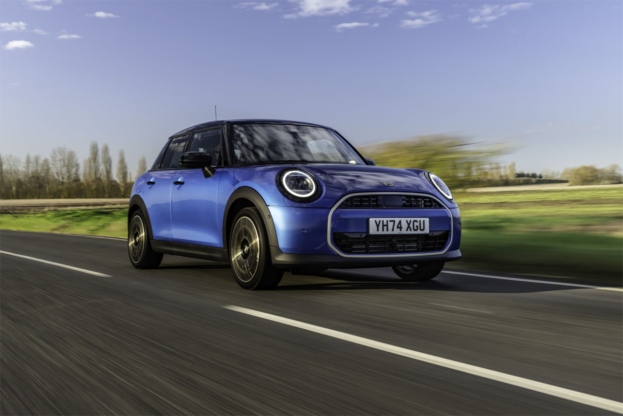  A blue Mini Cooper is driving down the street.