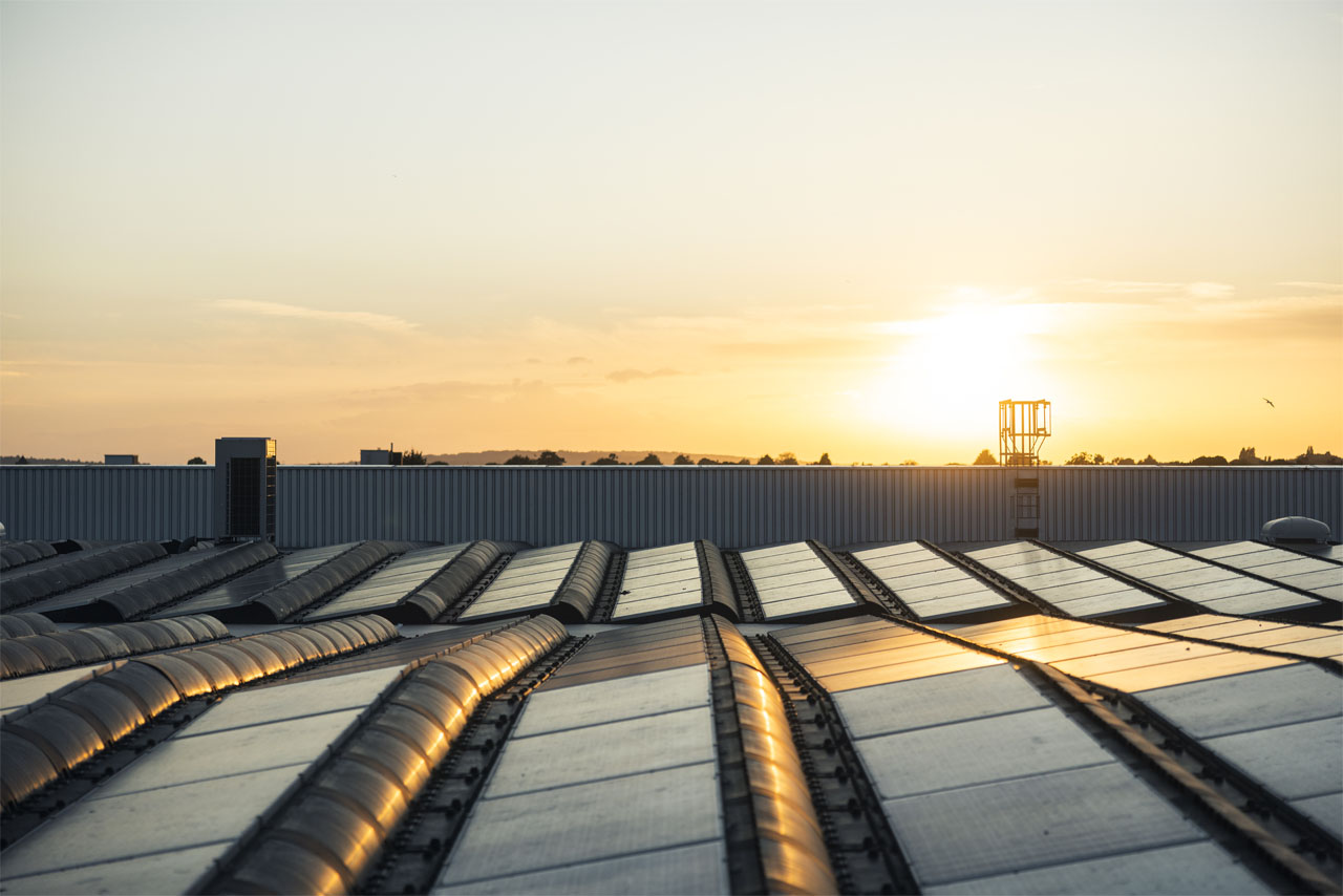 A sunset casts warm hues over a roof adorned with solar panels, highlighting sustainable energy use.