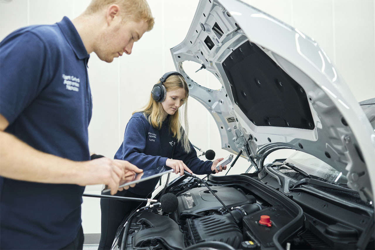 Two mechanics working on a vehicle in a garage, focused on repairs with tools scattered nearby.