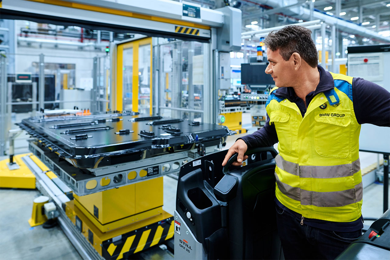 A man in a yellow safety vest stands next to a large machine.