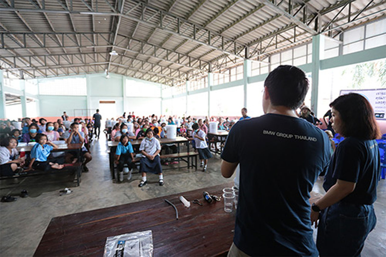 A man presenting to a large audience at a school in thailand.