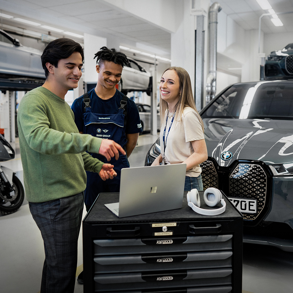 Three School leavers standing infront of a grey BMW iX.